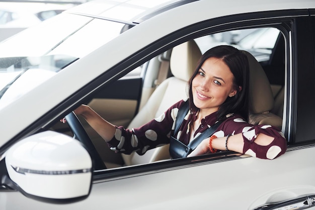 Vista lateral de la hermosa joven morena que está dentro del automóvil moderno