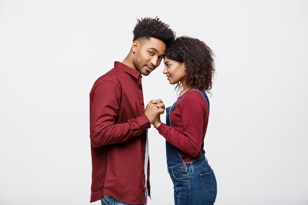 Vista lateral de la hermosa joven pareja afroamericana en camisas clásicas de la mano.