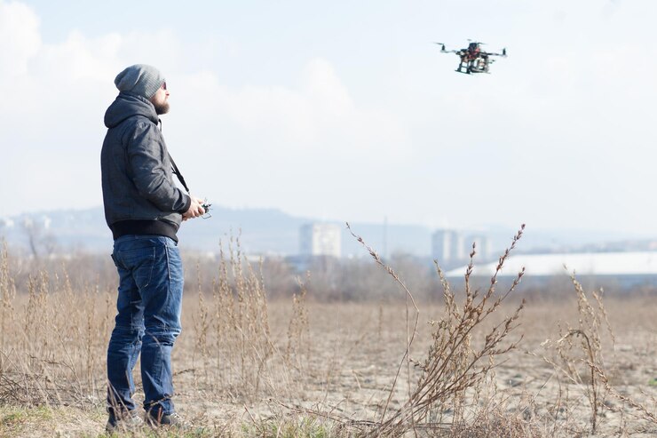Foto vista lateral de un hombre adulto volando un dron mientras está de pie en el campo contra el cielo