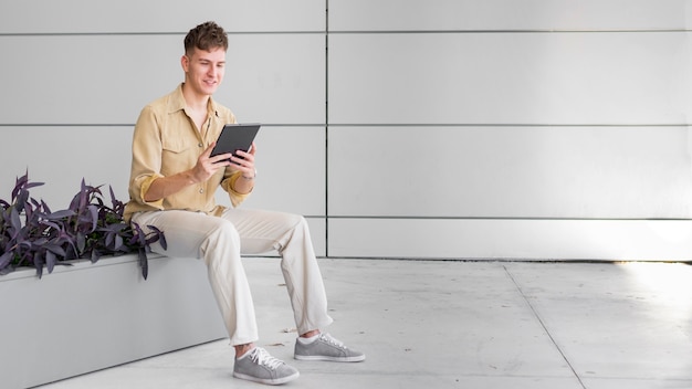 Foto vista lateral del hombre al aire libre mirando tableta con espacio de copia