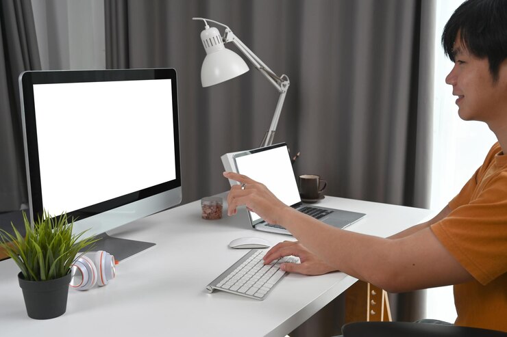 Foto vista lateral del hombre asiático feliz que trabaja en línea con la computadora en la oficina doméstica moderna