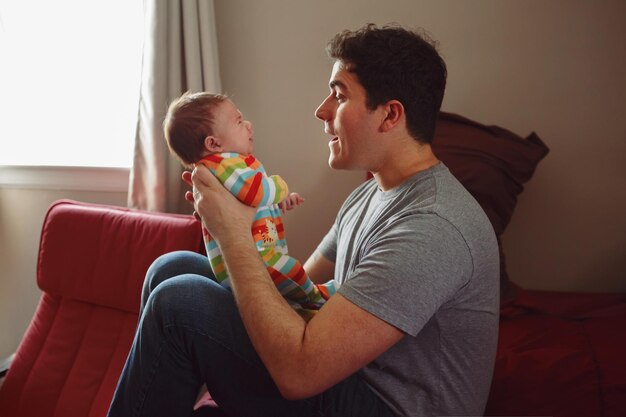 Foto vista lateral de un hombre con un bebé en casa