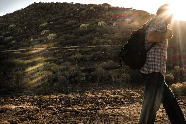 Vista lateral de un hombre caminando por la tierra durante la puesta de sol