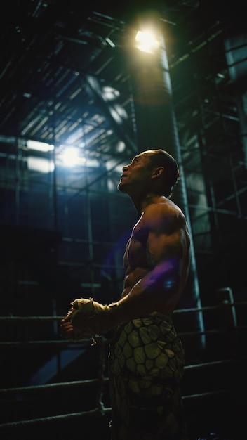 Vista lateral de un hombre sin camisa de pie en el ring de boxeo