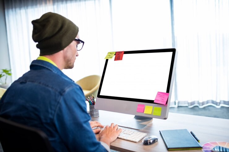 Foto vista lateral del hombre casual que trabaja en el escritorio de la computadora