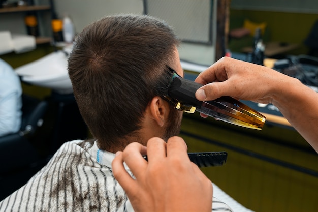 Foto vista lateral del hombre cortándose el pelo