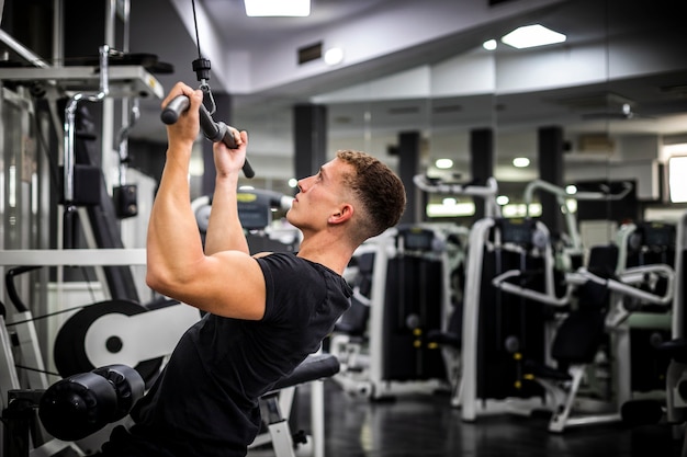 Foto vista lateral del hombre en el gimnasio levantando pesas