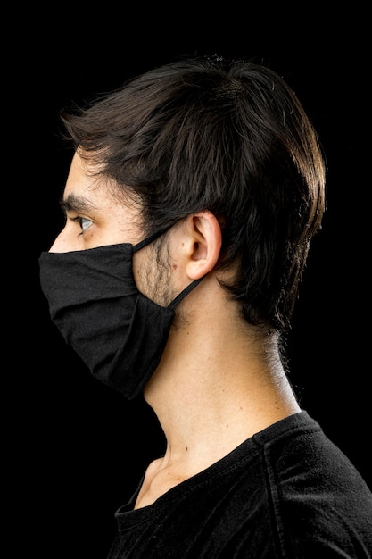 Vista lateral. Hombre joven con mascarilla negra.