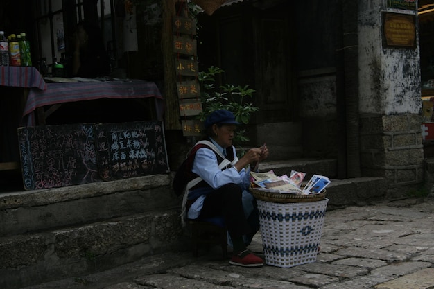 Vista lateral de un hombre maduro con una canasta agachado en la calle