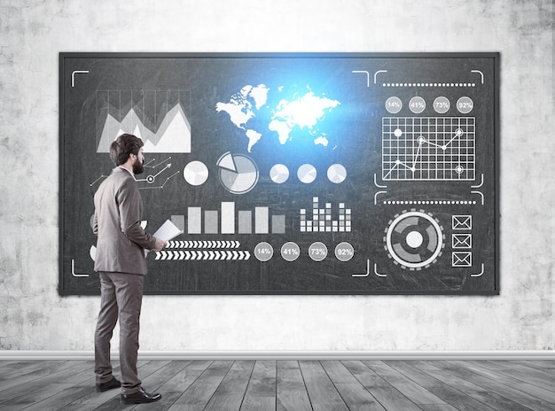 Vista lateral de un hombre de negocios barbudo sosteniendo papeles y mirando gráficos brillantes y un mapa del mundo en una pizarra en clase. Imagen tonada. Elementos de esta imagen proporcionados por la NASA