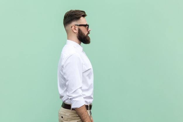 Vista lateral del hombre de negocios con gafas de sol negras de pie con una expresión facial seria y segura