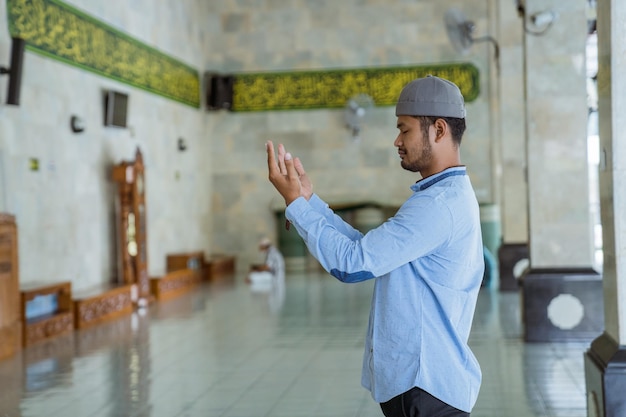 Foto vista lateral de un hombre orando en una mezquita