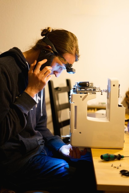 Vista lateral de un hombre reparando la máquina de coser