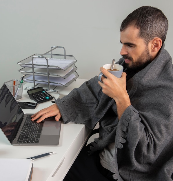 Foto vista lateral del hombre tomando café mientras trabaja desde casa