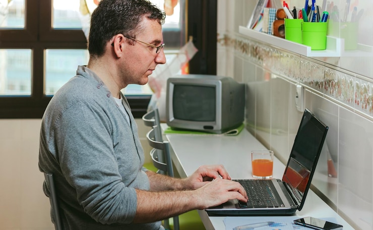 Foto vista lateral de un hombre usando una computadora portátil en la mesa en casa