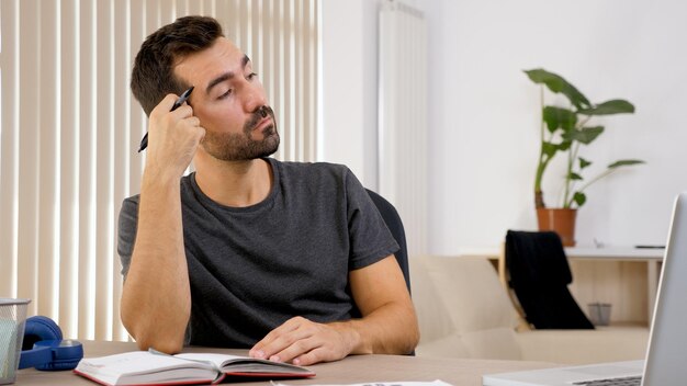 Foto vista lateral de un hombre usando una computadora portátil mientras está sentado en la mesa