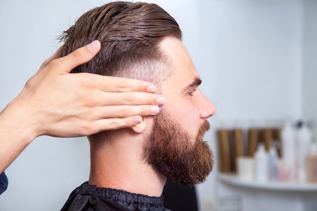 Vista lateral Homem barbudo sentado na barbearia.