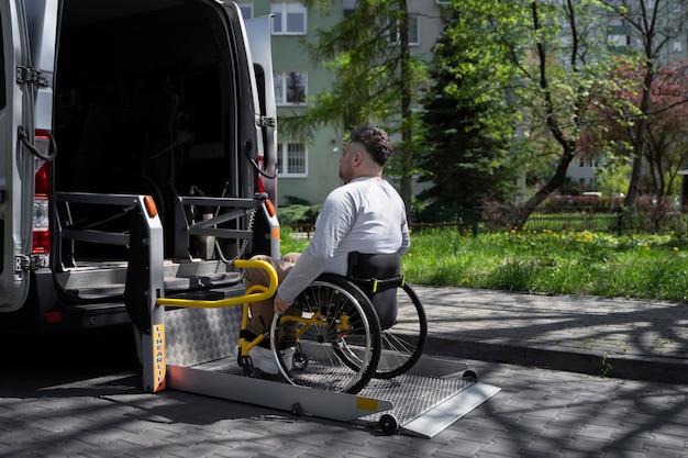 Vista lateral homem com deficiência em cadeira de rodas entrando no carro