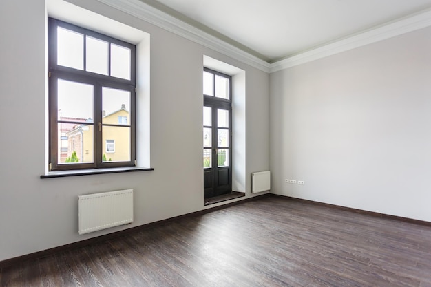 Vista lateral del interior del loft de la habitación sin amueblar con piso de madera, paredes blancas con luz natural brillante