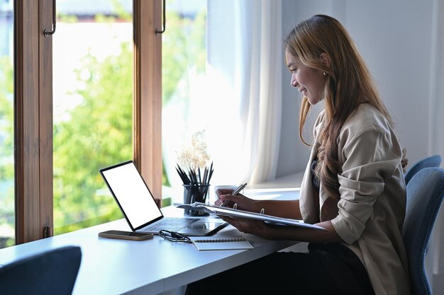 Vista lateral jovem empresária trabalhando com laptop em seu local de trabalho