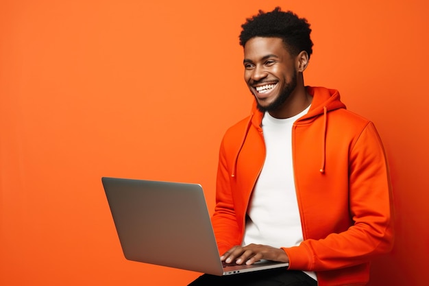 Vista lateral jovem sorridente homem afro-americano usa camiseta roupas casuais segurar uso ponto de trabalho em laptop computador navegação na internet isolado em laranja cor vermelha fundo estúdio