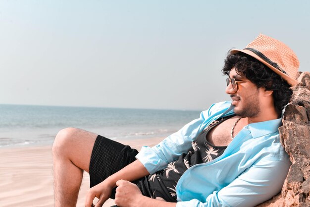 Vista lateral de un joven casual relajándose en la playa modelo pakistaní indio