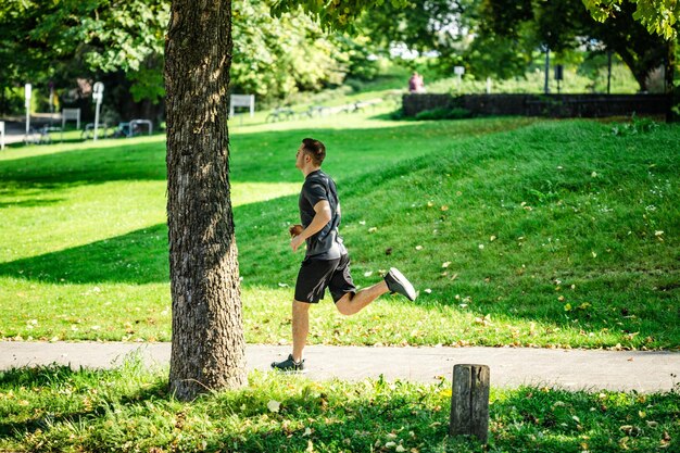Vista lateral de un joven corriendo por el sendero en el parque