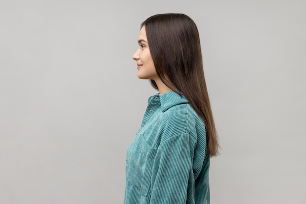 Vista lateral de una joven feliz y exitosa de pie mirando a la cámara con una sonrisa encantadora y con dientes