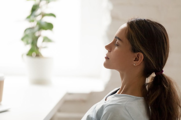 Vista lateral joven mujer de raza mixta relajándose con los ojos cerrados