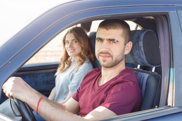 Vista lateral de la joven pareja hermosa tiene viaje en coche