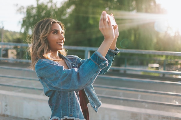 Foto vista lateral de una joven sonriente fotografiando mientras está de pie en la ciudad