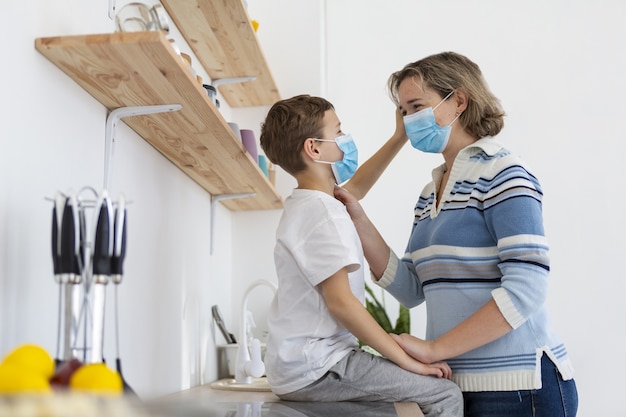 Vista lateral de la madre y el hijo con máscaras médicas