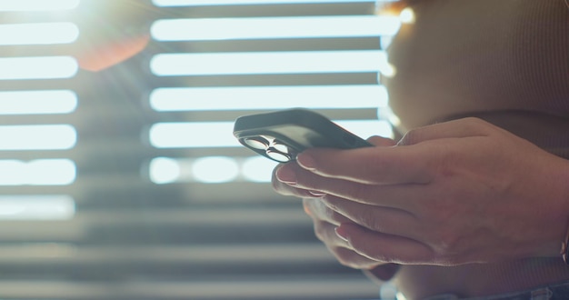 Vista lateral de la mano de una mujer usando un teléfono inteligente en casa Un primer plano de las manos femeninas enviando mensajes de texto en el teléfono inteligente