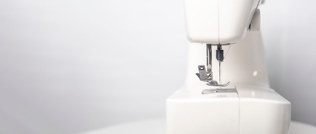 Vista lateral de la moderna máquina de coser blanca. banner con lugar para texto