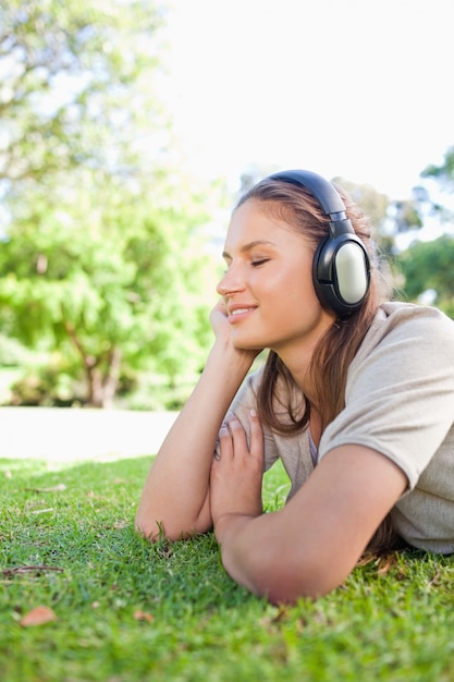 Vista lateral de una mujer disfrutando de la música en el césped