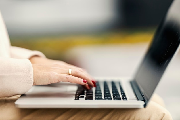 Vista lateral de una mujer escribiendo en la computadora portátil