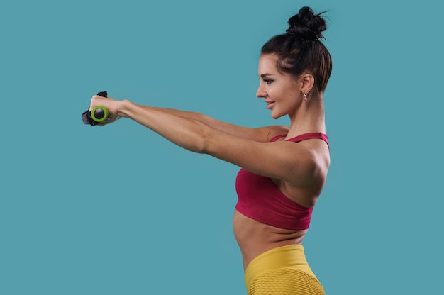 Vista lateral de una mujer en forma sosteniendo pesas con los brazos extendidos delante de ella