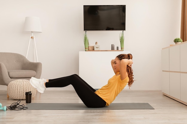 Vista lateral de la mujer haciendo ejercicio haciendo abdominales en casa