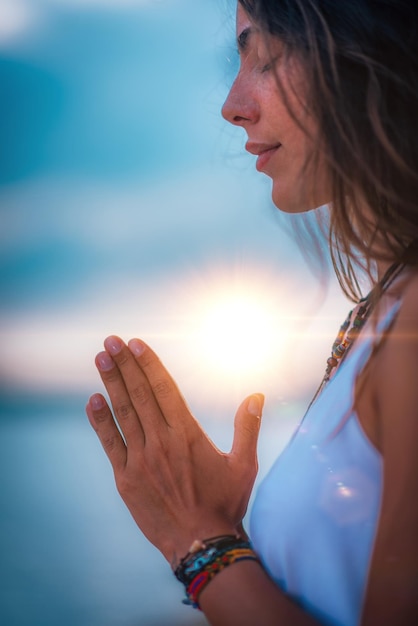 Foto vista lateral de una mujer haciendo yoga mientras está sentada contra el cielo durante la puesta de sol