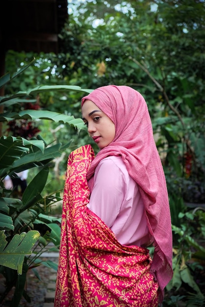Foto vista lateral de una mujer con hijab de pie contra las plantas
