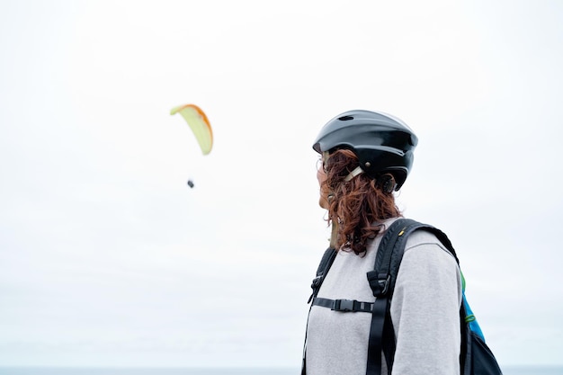 Vista lateral de una mujer irreconocible con equipo de parapente al aire libre. Vista panorámica de mujer aventurera practicando deportes de riesgo. Estilo de vida de aventura y deporte.