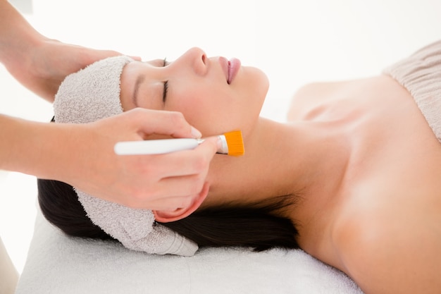 Vista lateral de una mujer joven atractiva que recibe masaje en el centro de spa