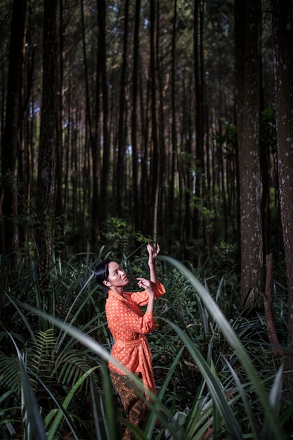 Foto vista lateral de una mujer joven bailando en el bosque