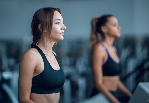 Vista lateral mujer joven en una caminadora en el gimnasio