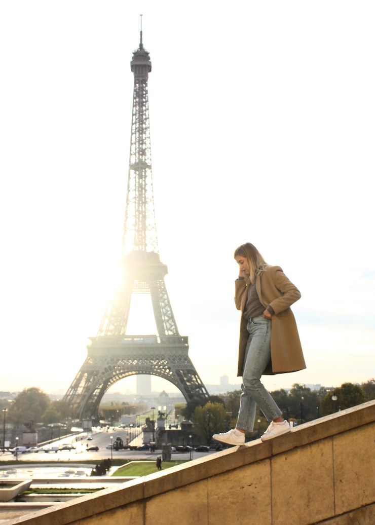 Foto vista lateral de una mujer joven caminando por la barandilla contra la torre eiffel