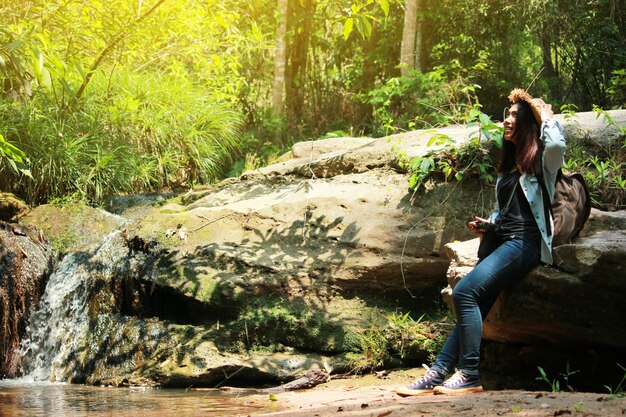 Foto vista lateral de una mujer joven fotografiando en el bosque