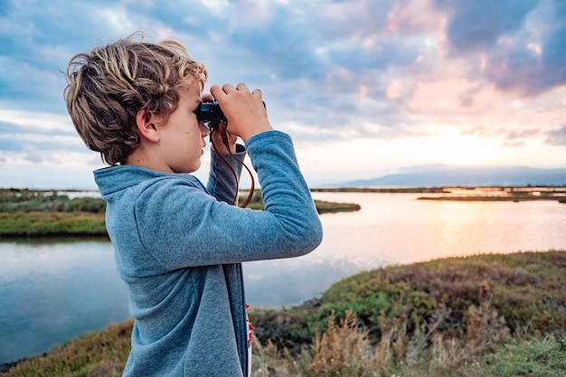 Vista lateral de una mujer joven fotografiando mientras está de pie en el campo