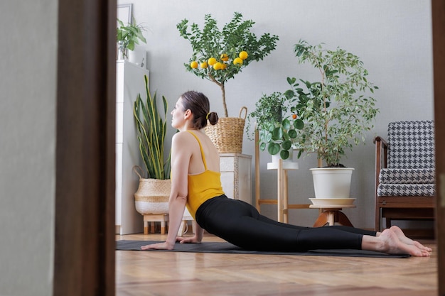 Vista lateral de una mujer joven haciendo ejercicio en casa