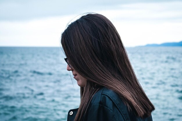 Foto vista lateral de una mujer joven por el mar