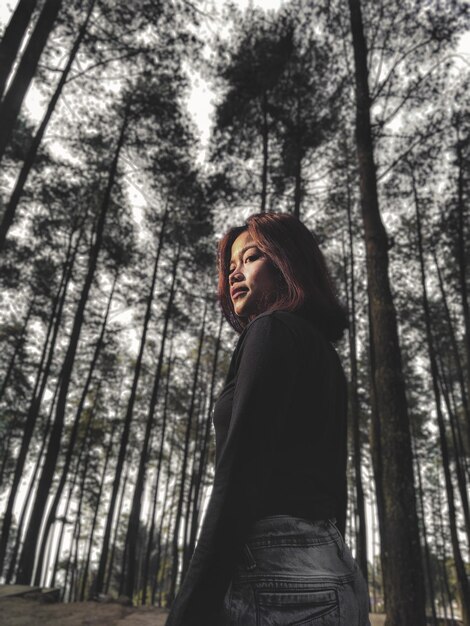 Foto vista lateral de una mujer joven de pie en el bosque